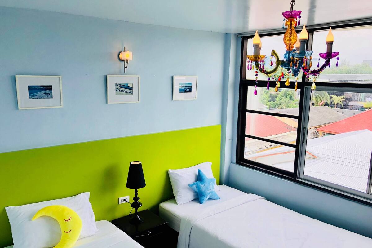Ett hotellrum med två sängar, ett fönster med utsikt, en kristallkrona och väggmonterade lampor.