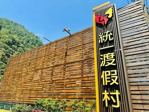 A building with a wooden slatted facade and a vertical sign with Chinese characters. - Uni Resort KU-KUAN (Taichung)