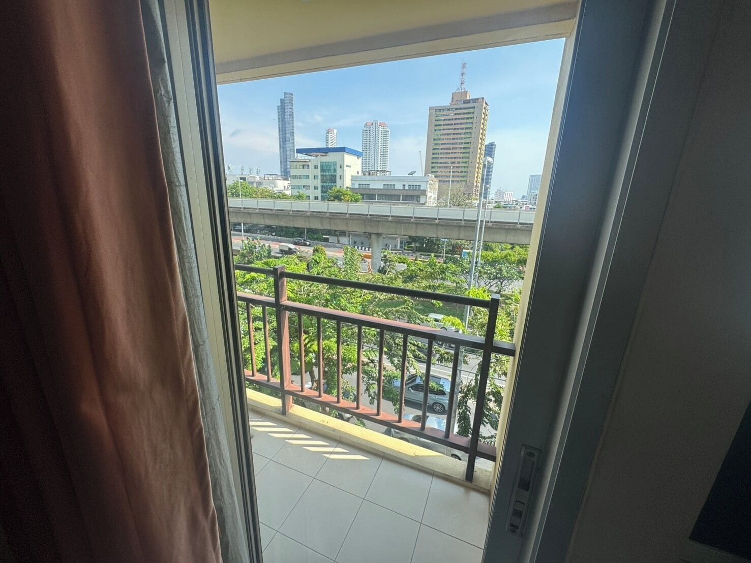 A balcony with a view of a cityscape, including high-rise buildings and a bridge.