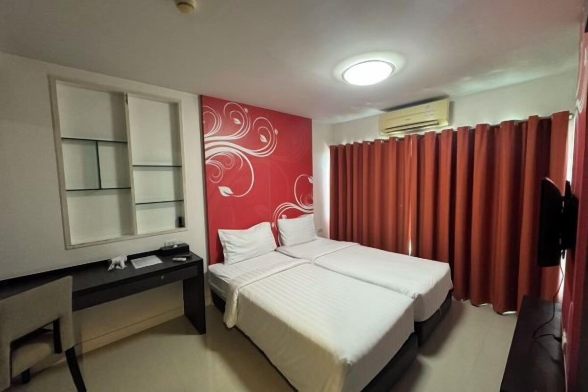 Una habitación de hotel con una cama, un escritorio, un espejo y un televisor.
