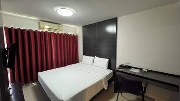 A hotel room with a bed, a desk, a chair, and a large mirror.