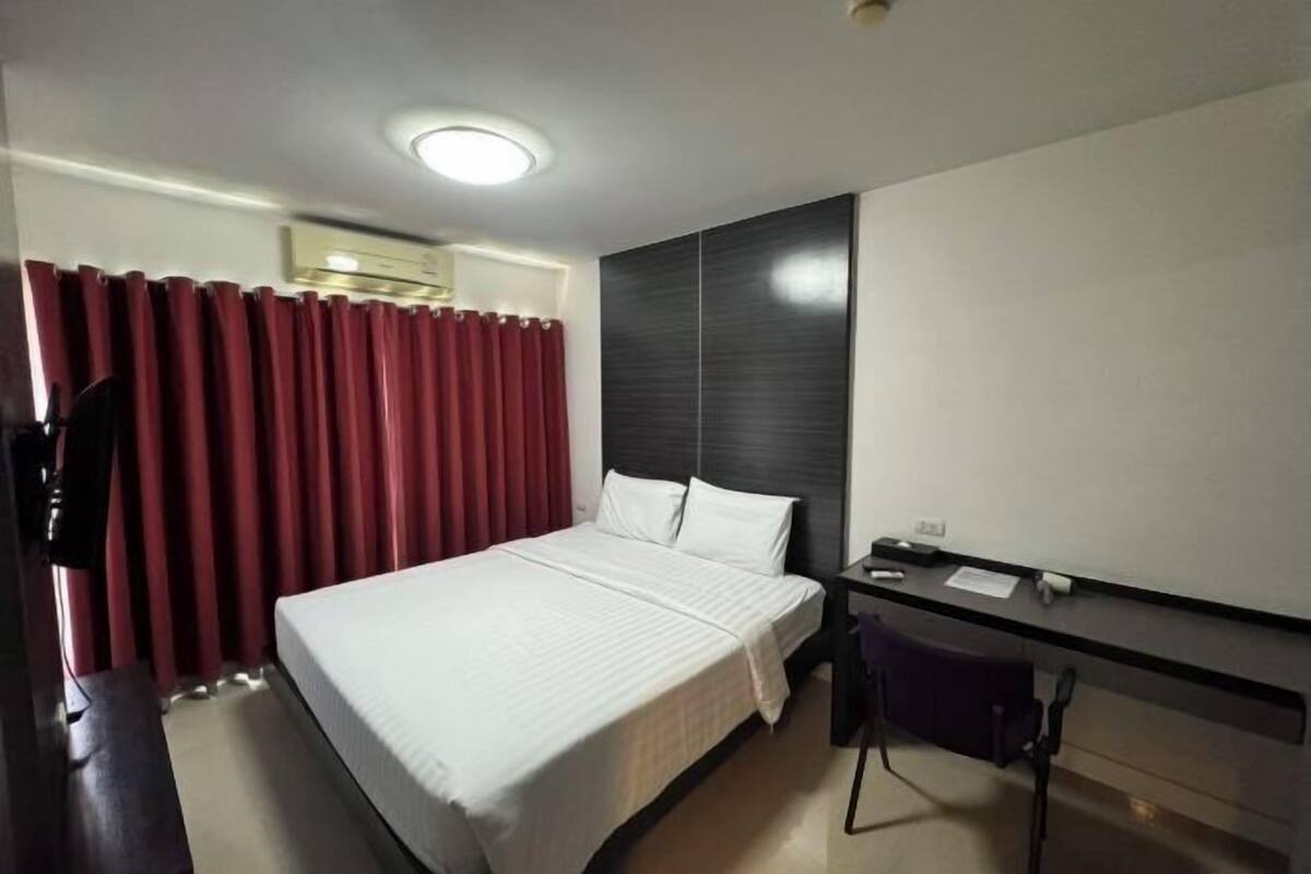 A hotel room with a bed, a desk, a chair, and a wardrobe.