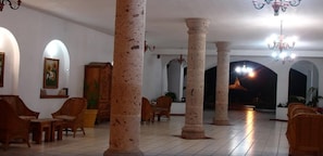 Un vestíbulo amplio con altas columnas de piedra, muebles de madera y arcos.