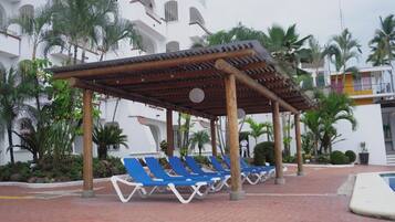 Alberca al aire libre, sombrillas en la alberca y camastros