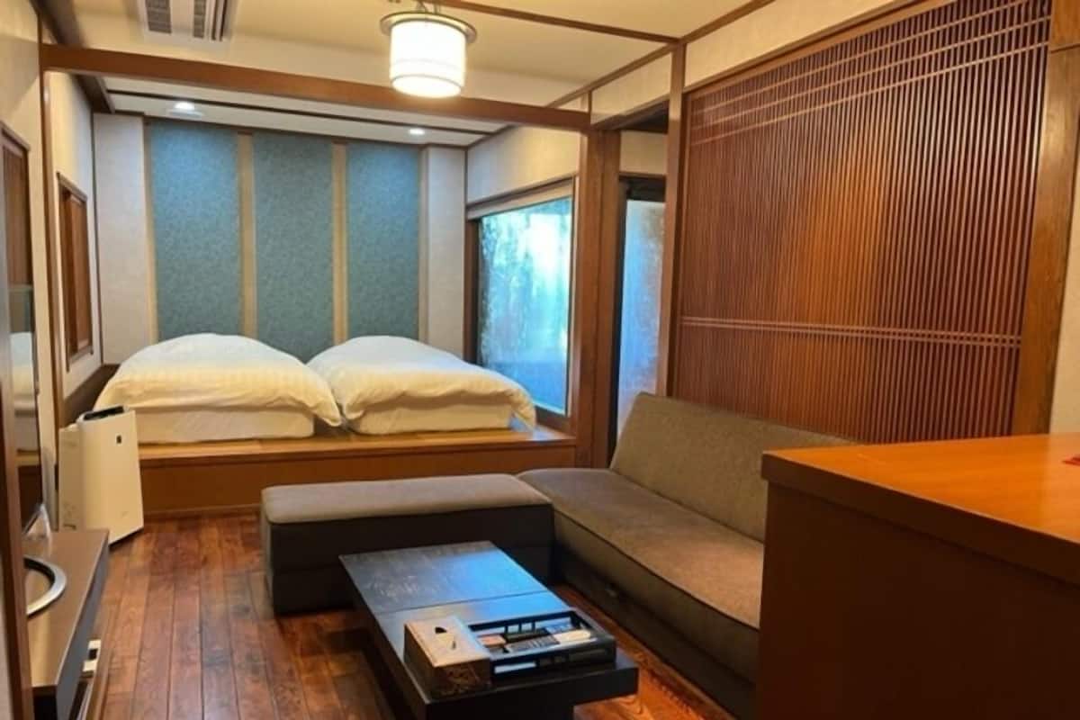 Une pièce comprenant un lit, un canapé, une petite table et une cloison en bois.