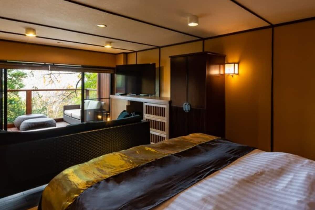 Une chambre moderne avec un grand lit, une télévision et un coin salon près de la fenêtre.