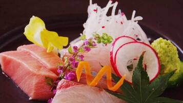 Ein Teller mit Sashimi, Rettichscheiben und einer Dekoration aus Blumen und Blättern.