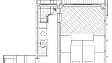 Un plan d’étage d’une chambre d’hôtel comprenant une salle de bain, un petit coin salon et un grand lit.