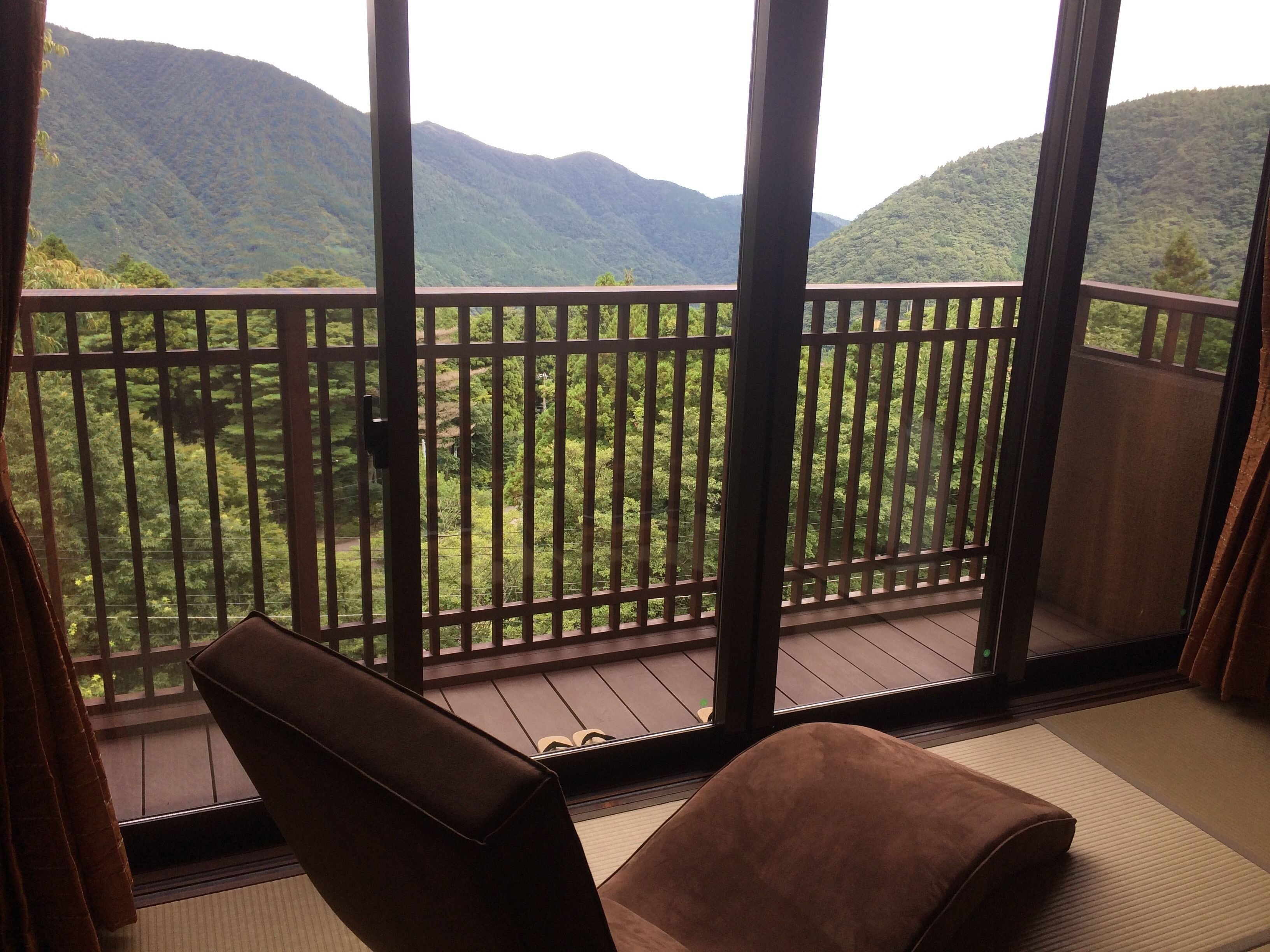 A room with a view of a mountainous landscape through a wooden balcony.