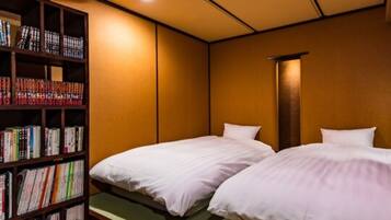 Ein Hotelzimmer mit zwei Betten, einem Bücherregal und einer traditionellen japanischen Wand.