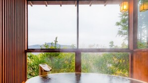 Un jacuzzi con interior de madera y vistas al verdor exterior.
