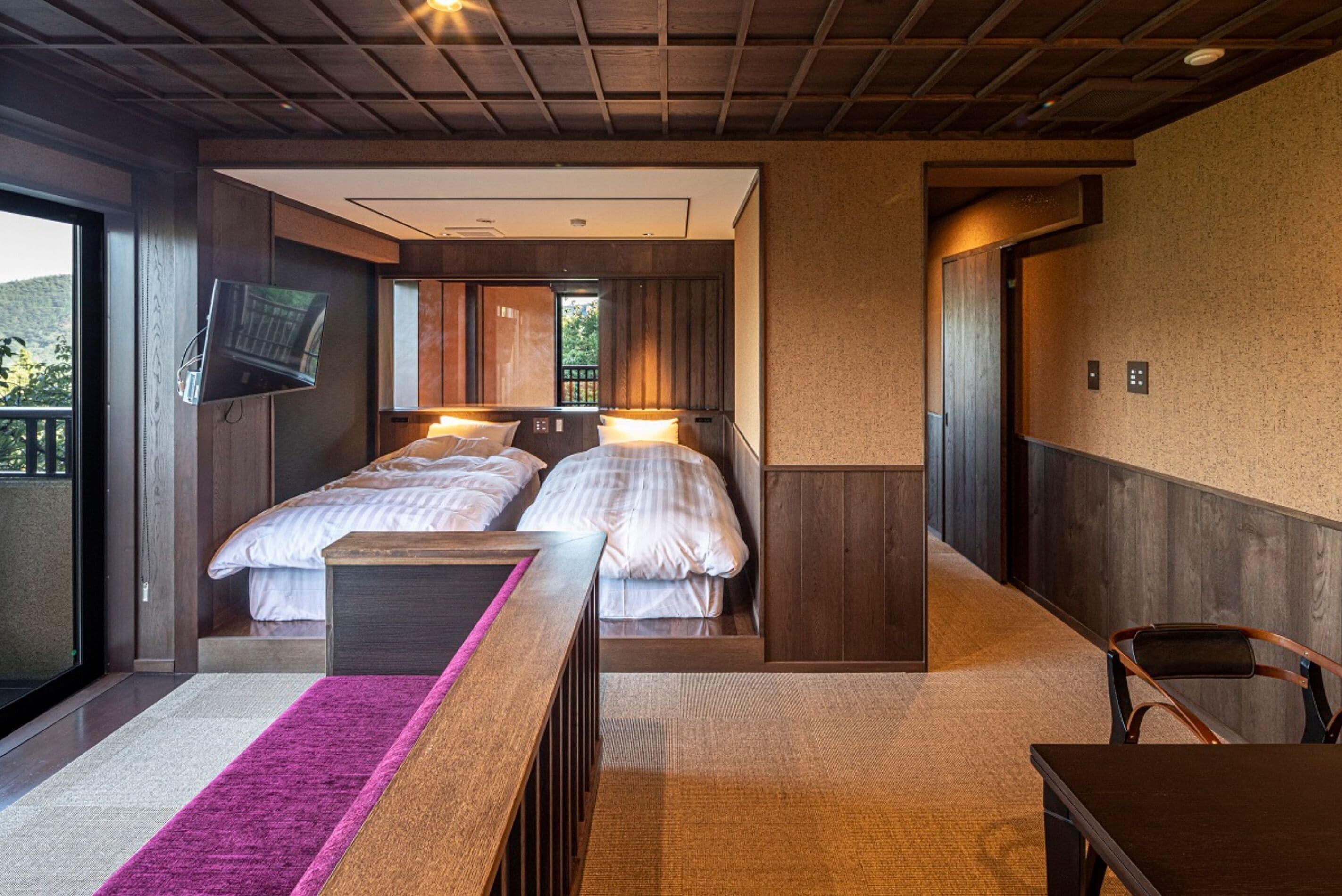 Una camera da letto moderna con due letti, una TV a parete e vista sull'esterno.