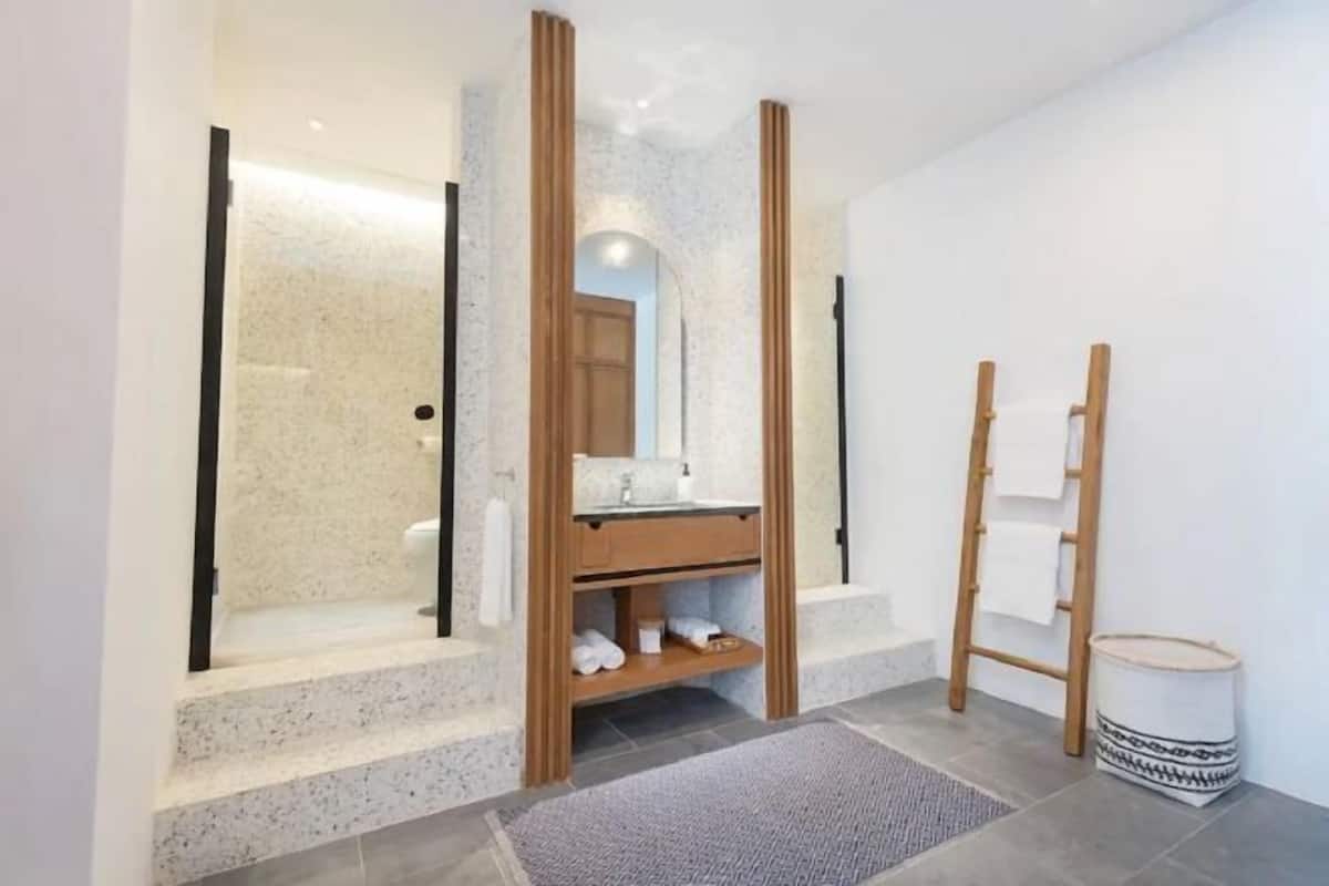 Badkamer | Een douche, designer toiletartikelen, een haardroger, badjassen