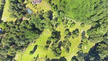 An aerial view of a golf course with multiple green areas, trees, and a small building.