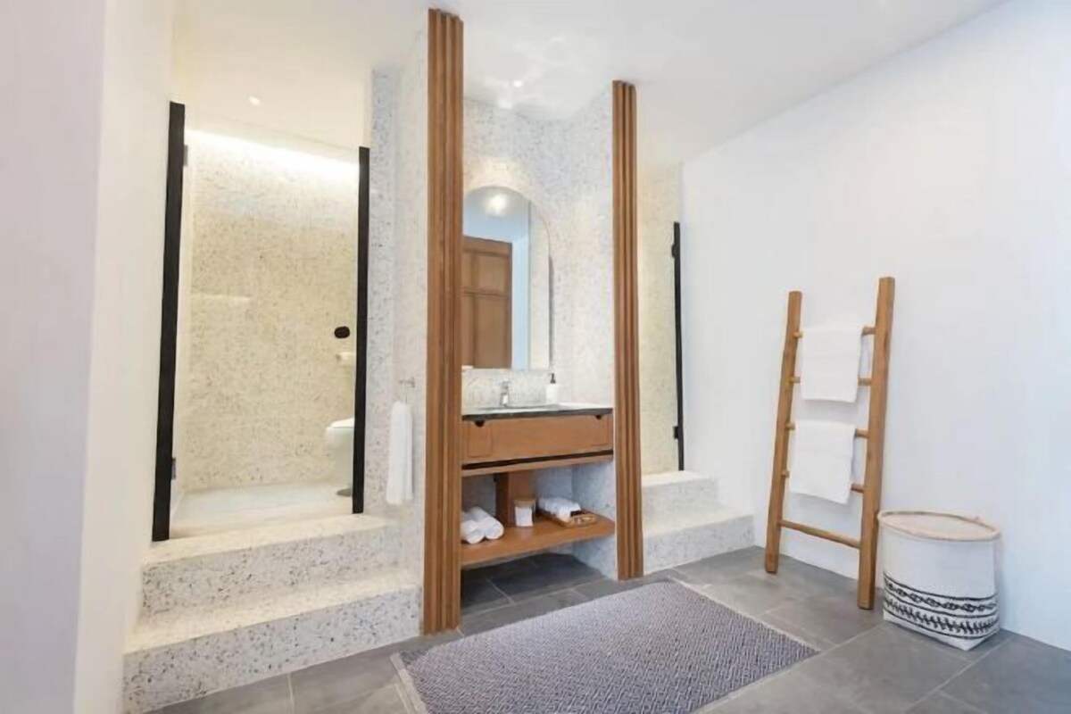 A bathroom with a shower, a sink, a mirror, and a towel rack.