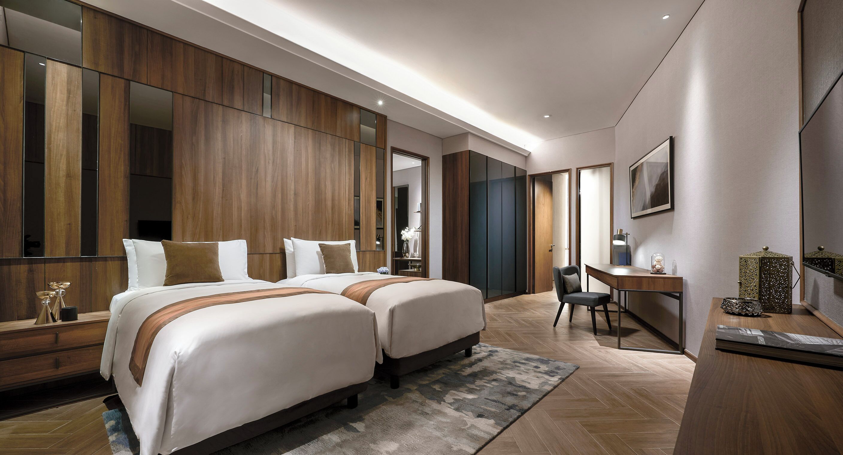 A modern hotel room with two beds, a desk, and a large mirror.
