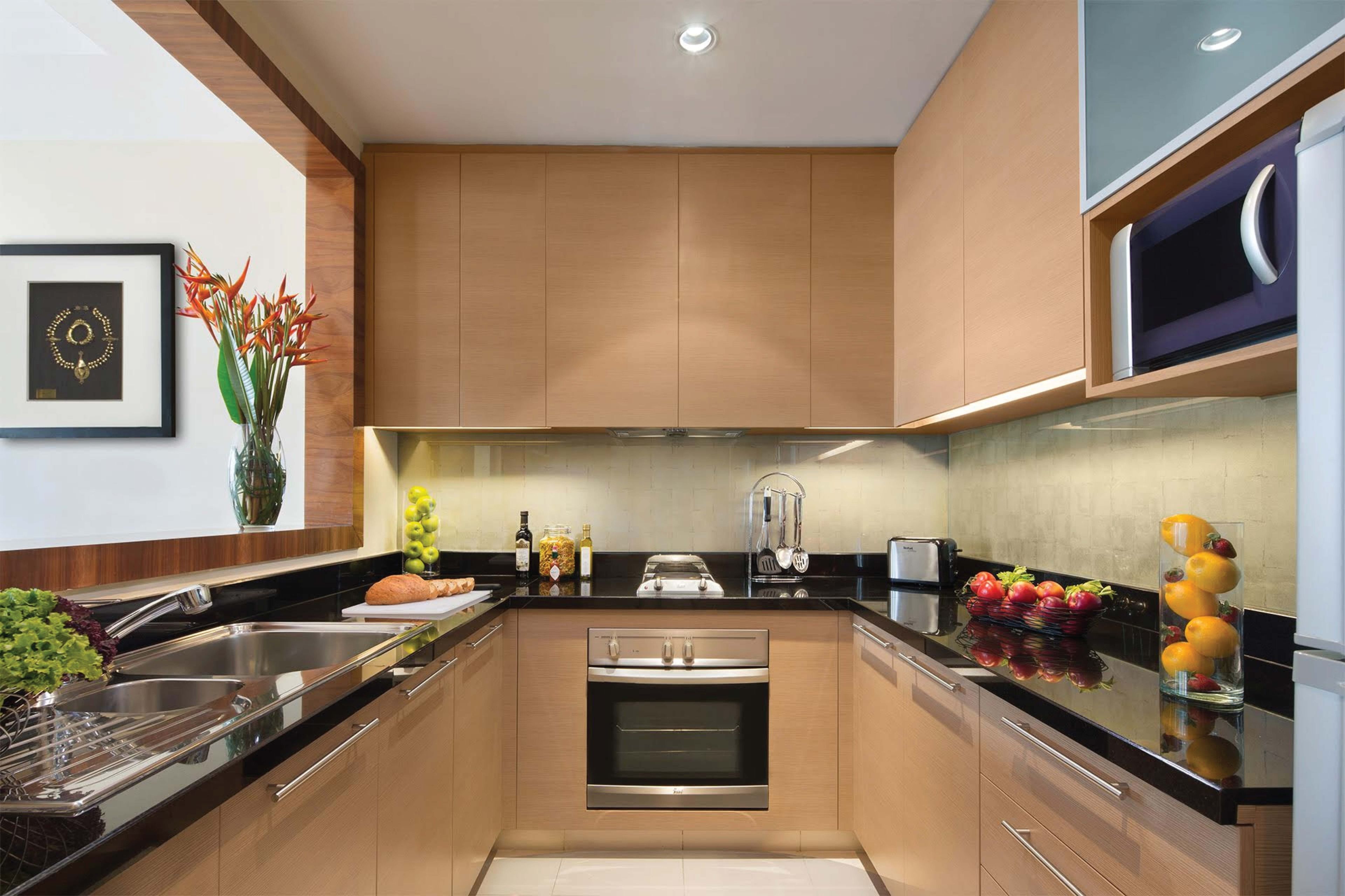 A modern kitchen with stainless steel appliances, wooden cabinets, a built-in oven, and a black countertop.