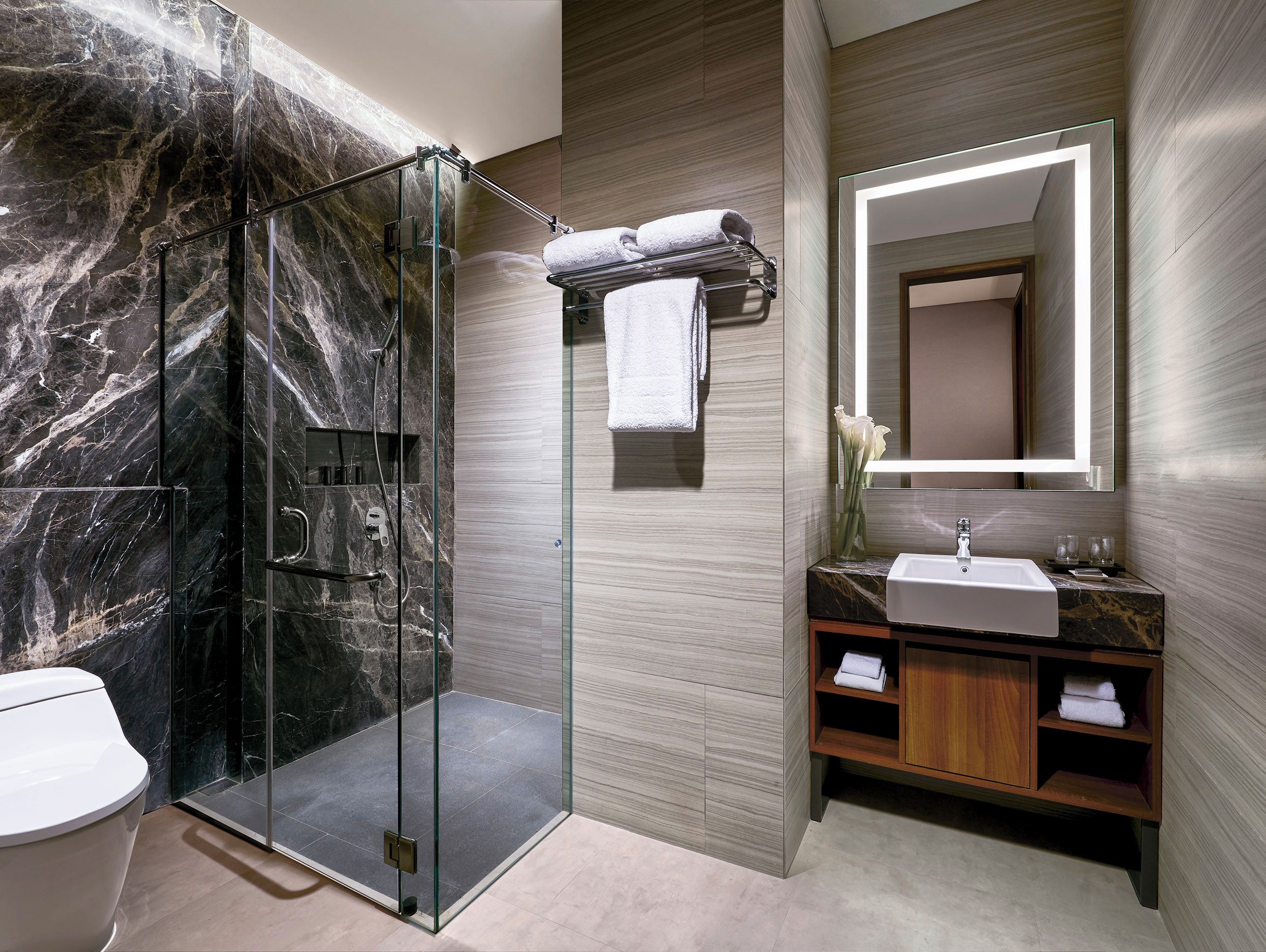 A modern bathroom with a glass-enclosed shower, a vanity with a mirror, and a toilet.