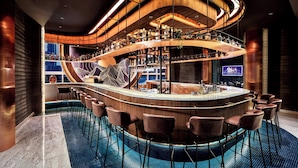 A modern bar with a curved design, multiple levels, and a pool area. - Oakwood Premier Cozmo Jakarta (Jakarta)