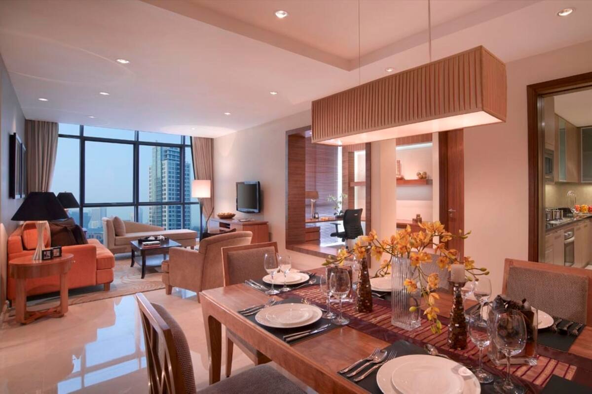 A modern hotel room with a dining area, a living room, and a kitchen.