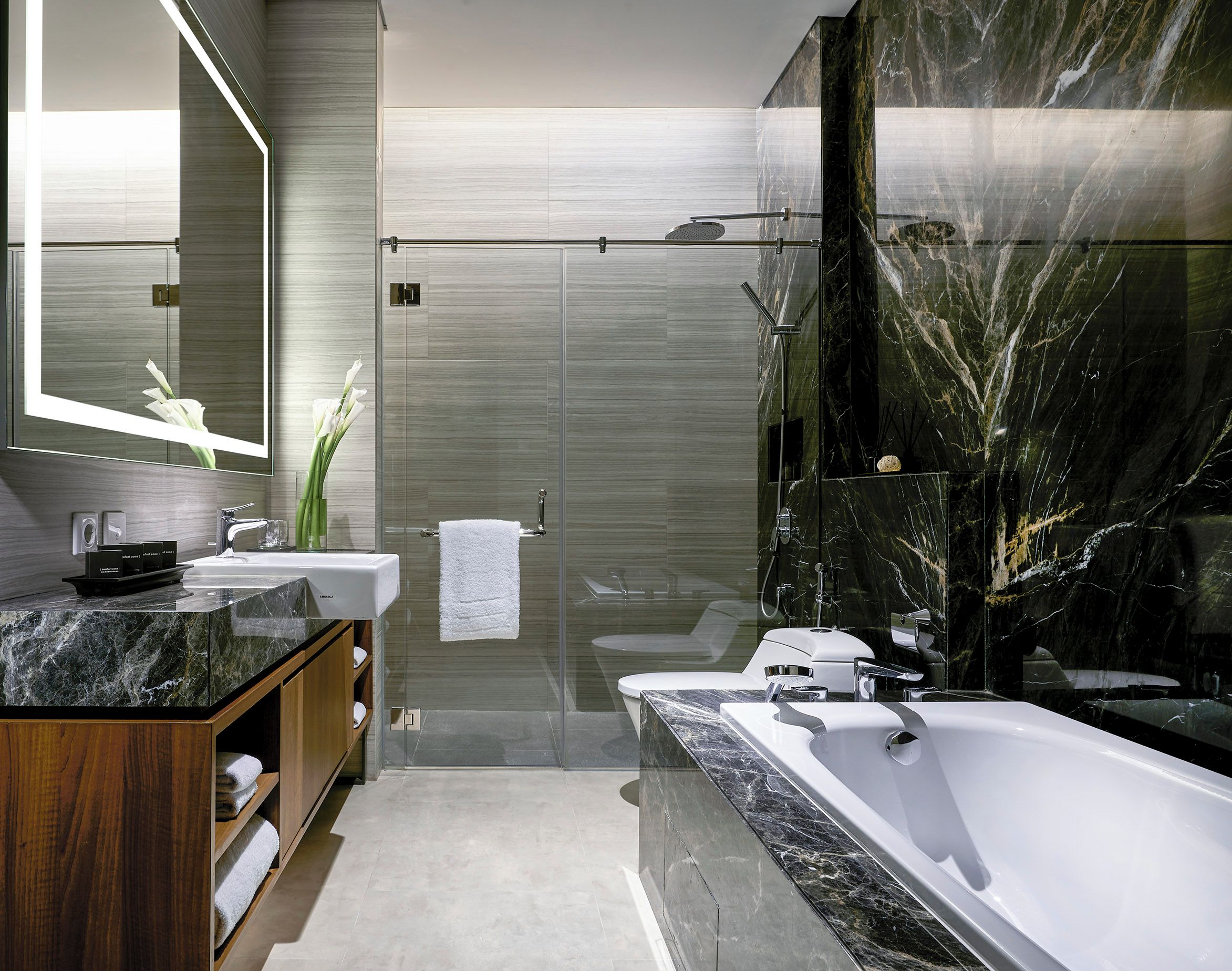 Ein modernes Badezimmer mit einer großen Badewanne, einer einbruchsicheren Dusche und einem Waschtisch mit Marmorplatte.