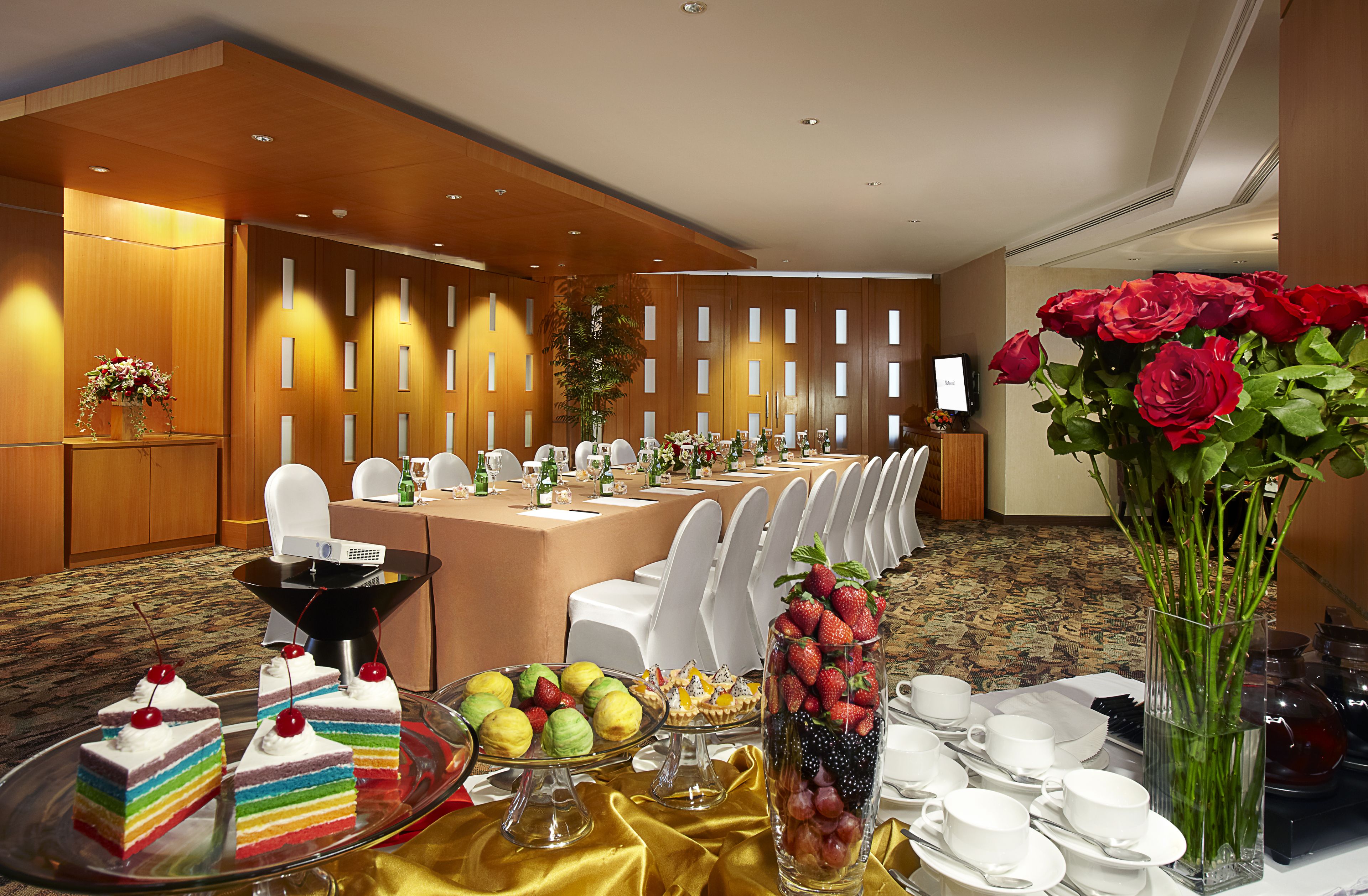 Een balzaal met een lange tafel gedekt voor een formeel evenement, met een verscheidenheid aan desserts en fruit.