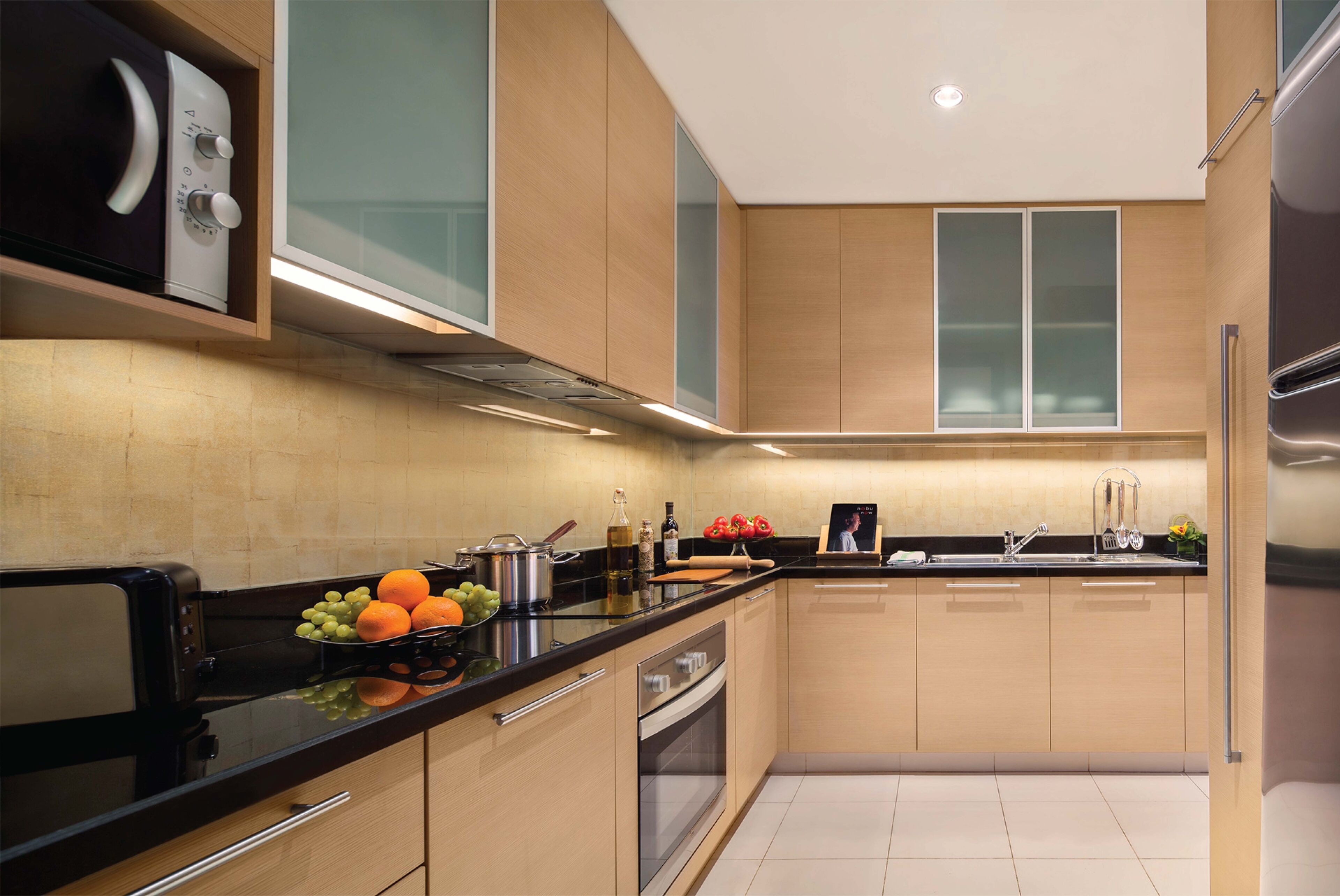 Una cocina moderna con encimera negra, electrodomésticos de acero inoxidable y armarios de madera.