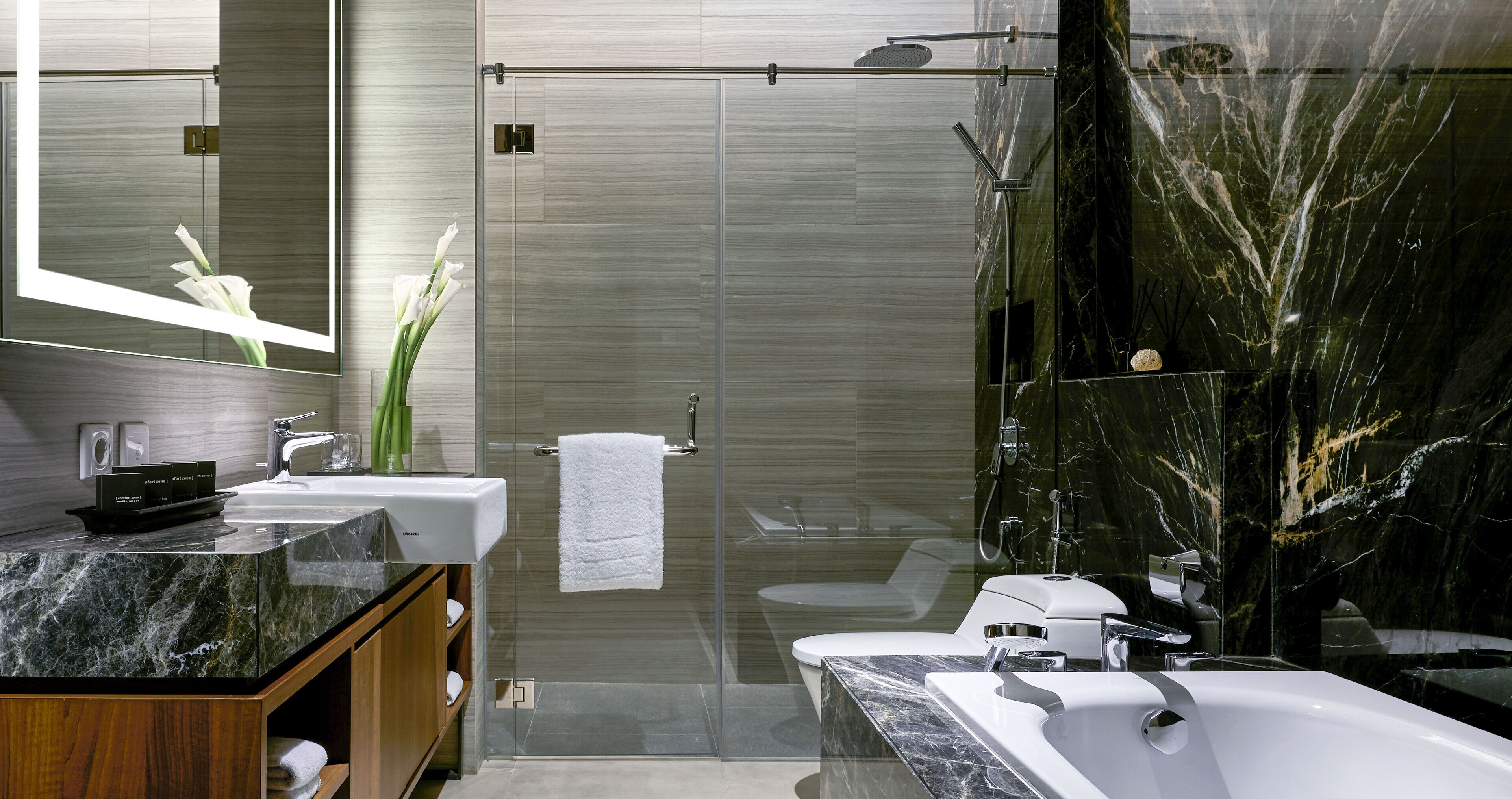 A modern bathroom with a glass-enclosed shower, a marble countertop, and a large mirror.