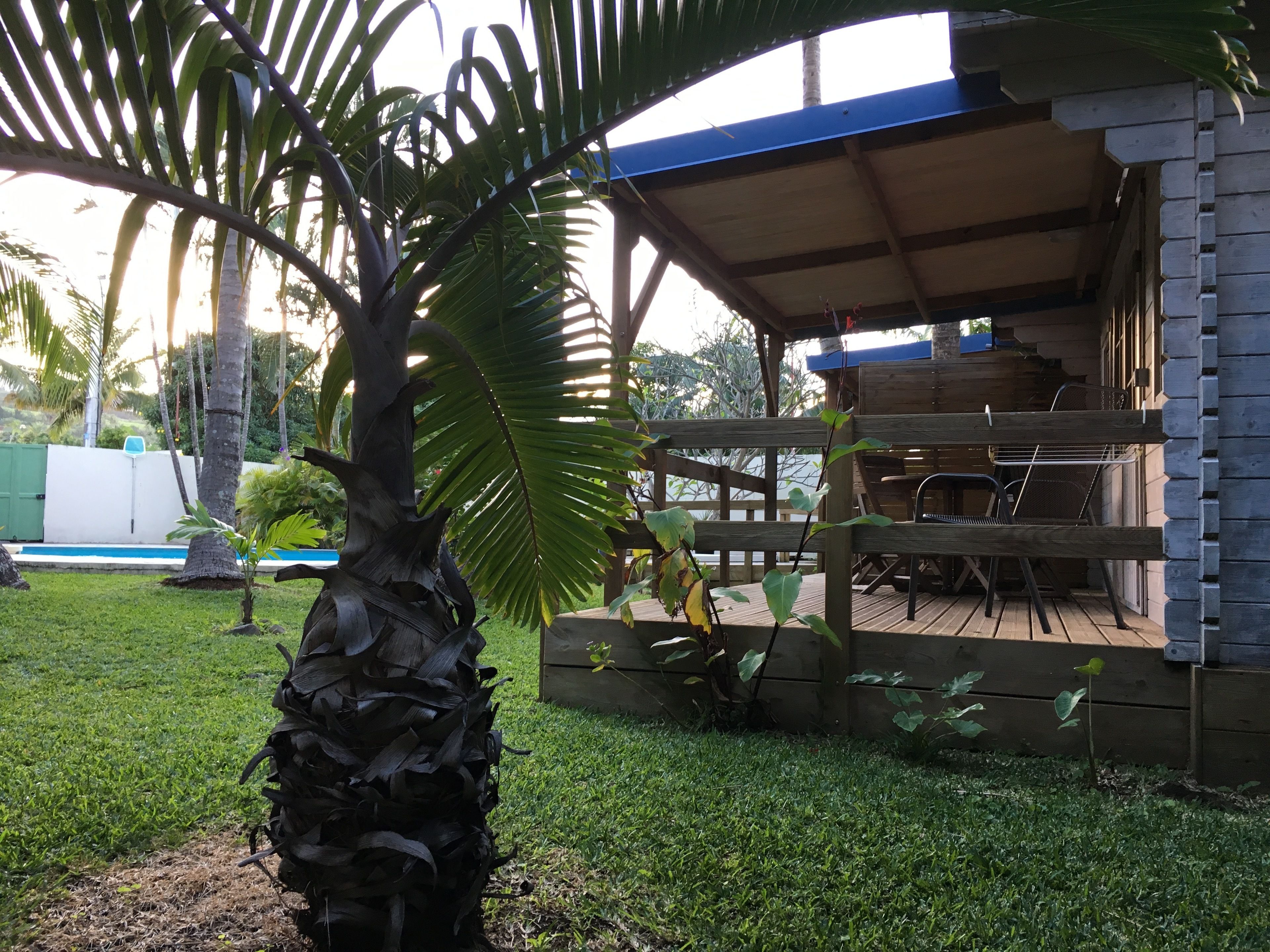A covered outdoor area with a wooden deck, a barbecue grill, and a small pool.