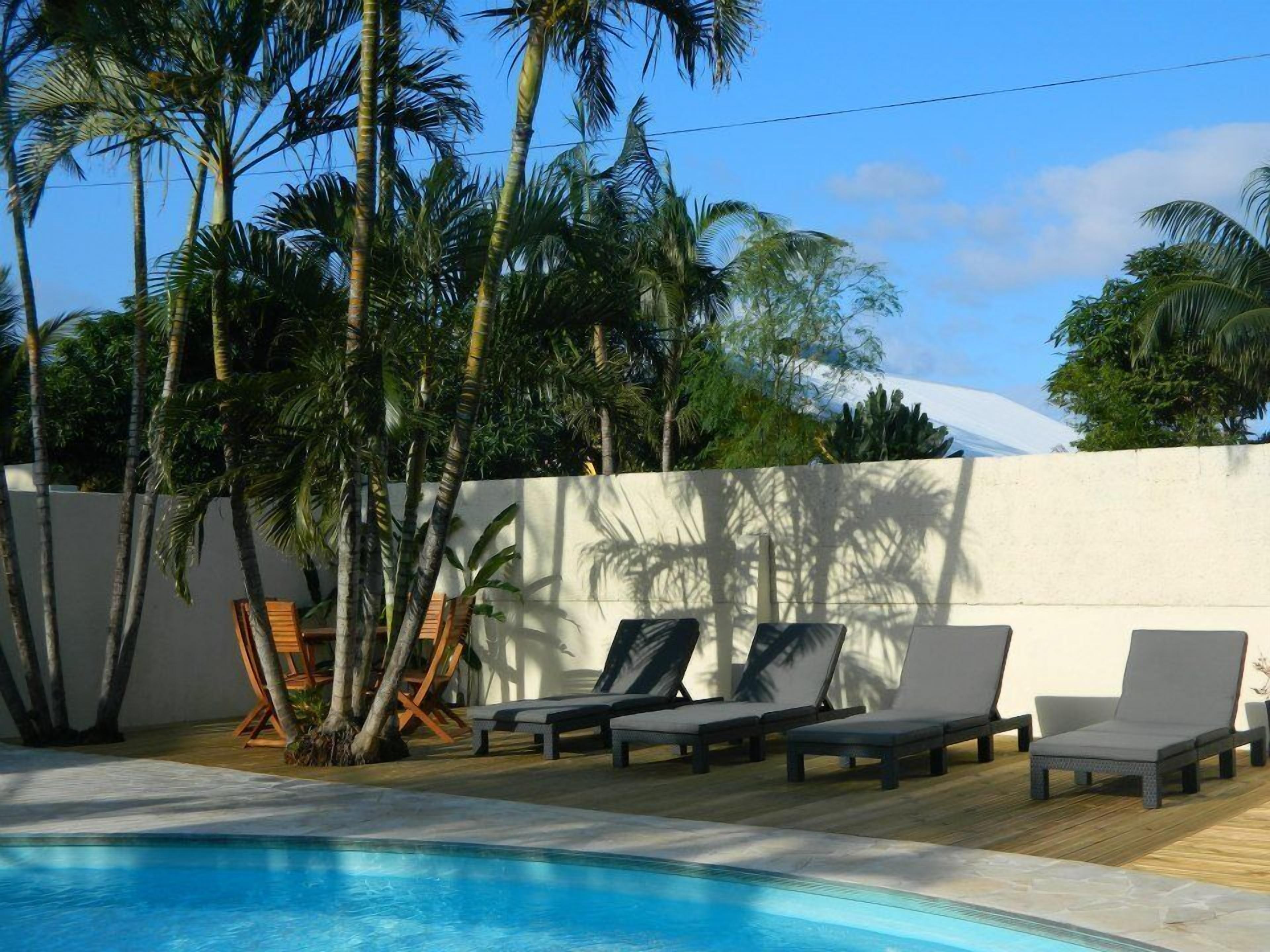 A poolside area with lounge chairs and palm trees.