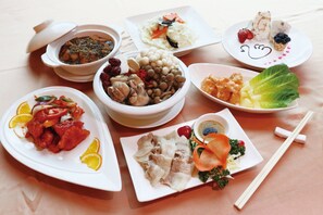 A variety of dishes on white plates, including a bowl of mushrooms, a plate with meat, and a plate with vegetables. - Uni-Resort Mawutu (Guanxi)