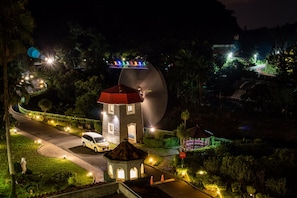 A hotel with a distinctive tower, a curved building, and a well-lit pathway. - Uni-Resort Mawutu (Guanxi)