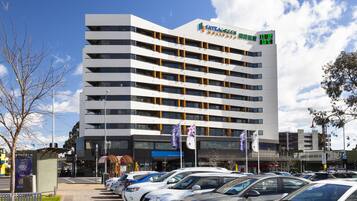 A multi-story hotel with a modern design, featuring balconies and large windows.