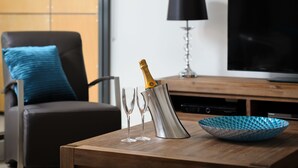 A wooden table with a champagne bottle, two glasses, and a decorative bowl. - Park Avenue - IKON Glen Waverley (Glen Waverley)