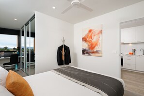 A modern bedroom with a large bed, a desk, and a view of the city. - Park Avenue - IKON Glen Waverley (Glen Waverley)