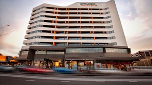 A multi-story hotel with a modern design, featuring a prominent entrance and a sign indicating it is an 'ExtraGreen Holiday Inn'. - Park Avenue - IKON Glen Waverley (Glen Waverley)