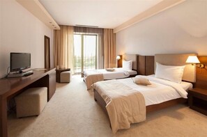 A hotel room with two beds, a desk with a television, and a window with curtains. - Yesterday Hotel (Bucharest)