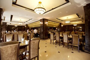 A spacious dining area with high ceilings, chandeliers, and a central bar area.
