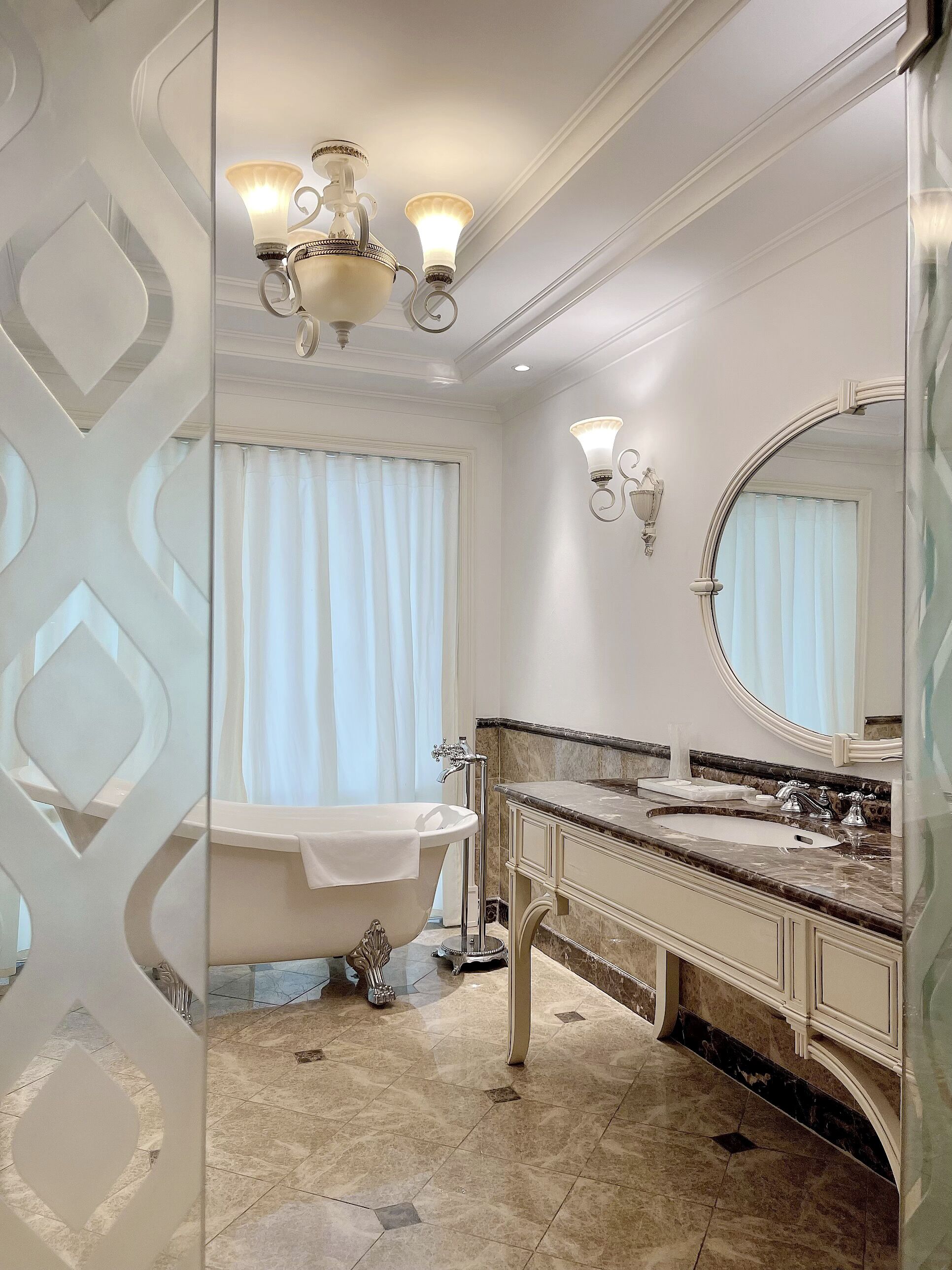 A bathroom with a freestanding bathtub, a large mirror, and a marble countertop.