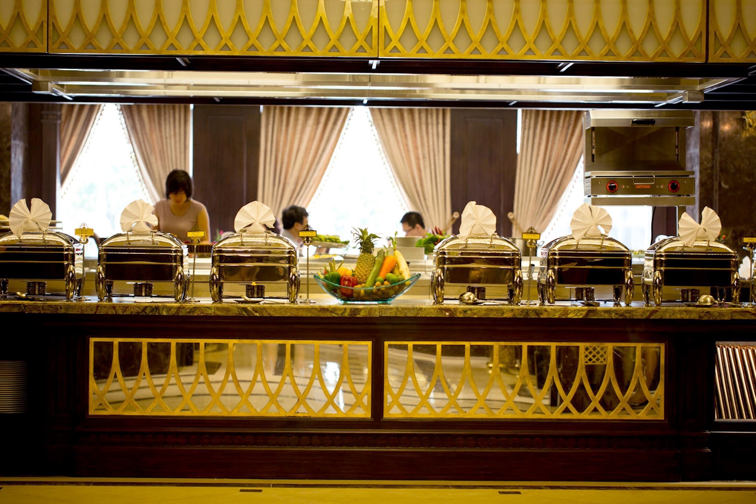 A buffet setup with covered serving dishes and a bowl of fruit in the center.