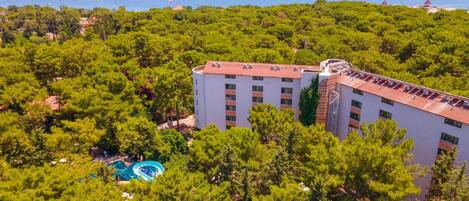 Un hotel con piscina rodeado de vegetación exuberante y vista al mar.