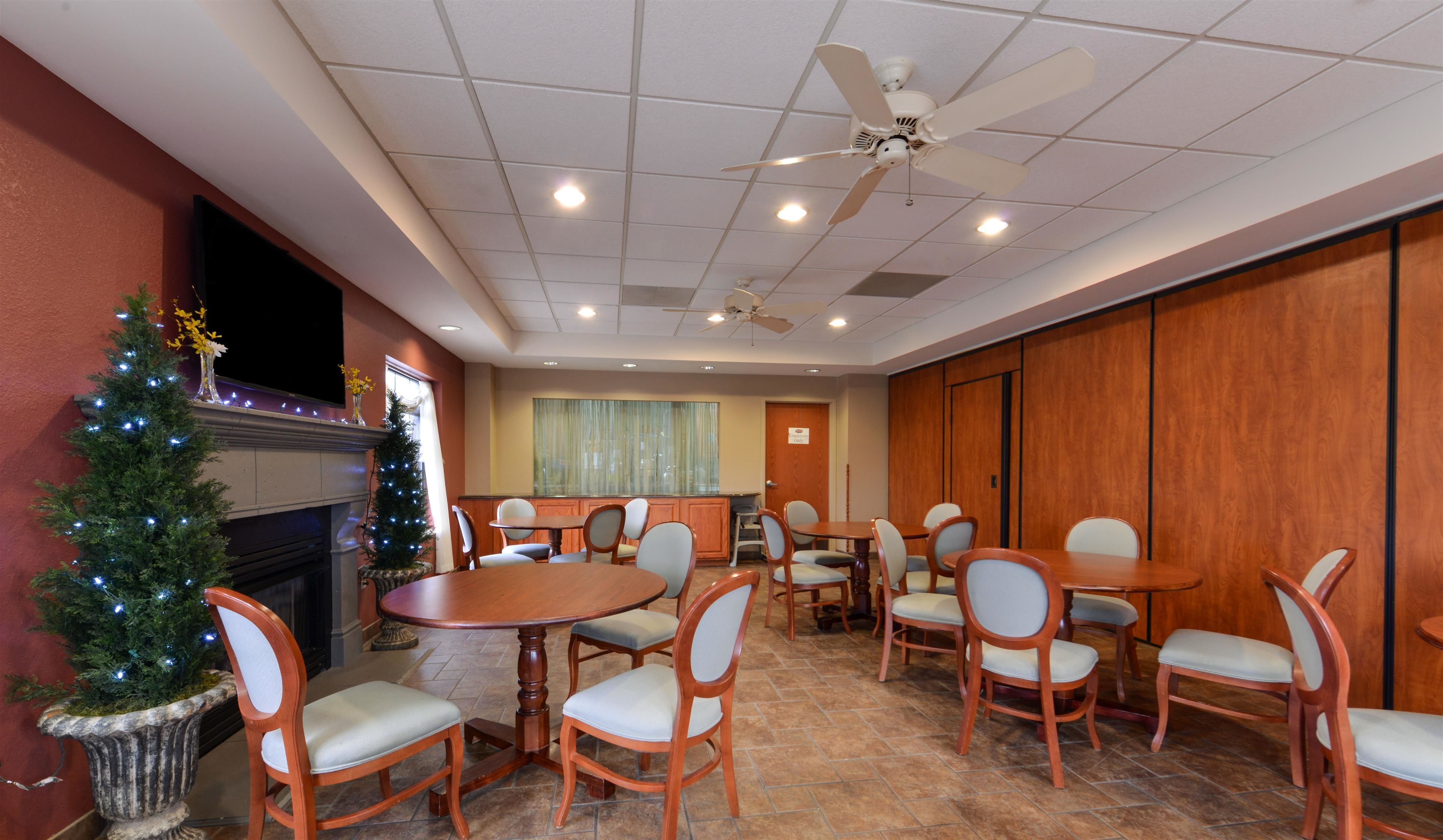 A conference room with multiple tables and chairs, a ceiling fan, and a Christmas tree.