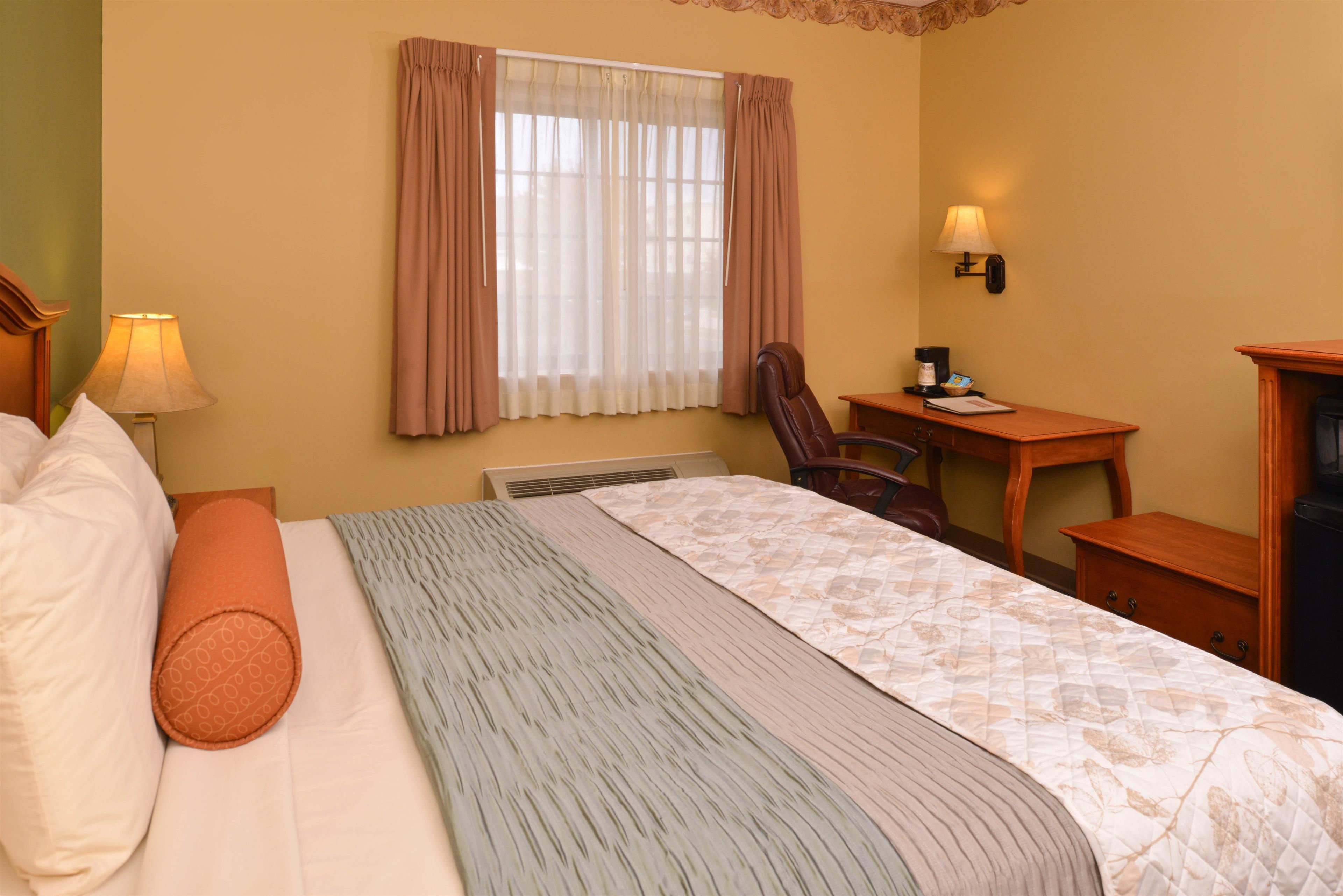 Ein Hotelzimmer mit Bett, Schreibtisch, Stuhl, Lampe und Heizung.