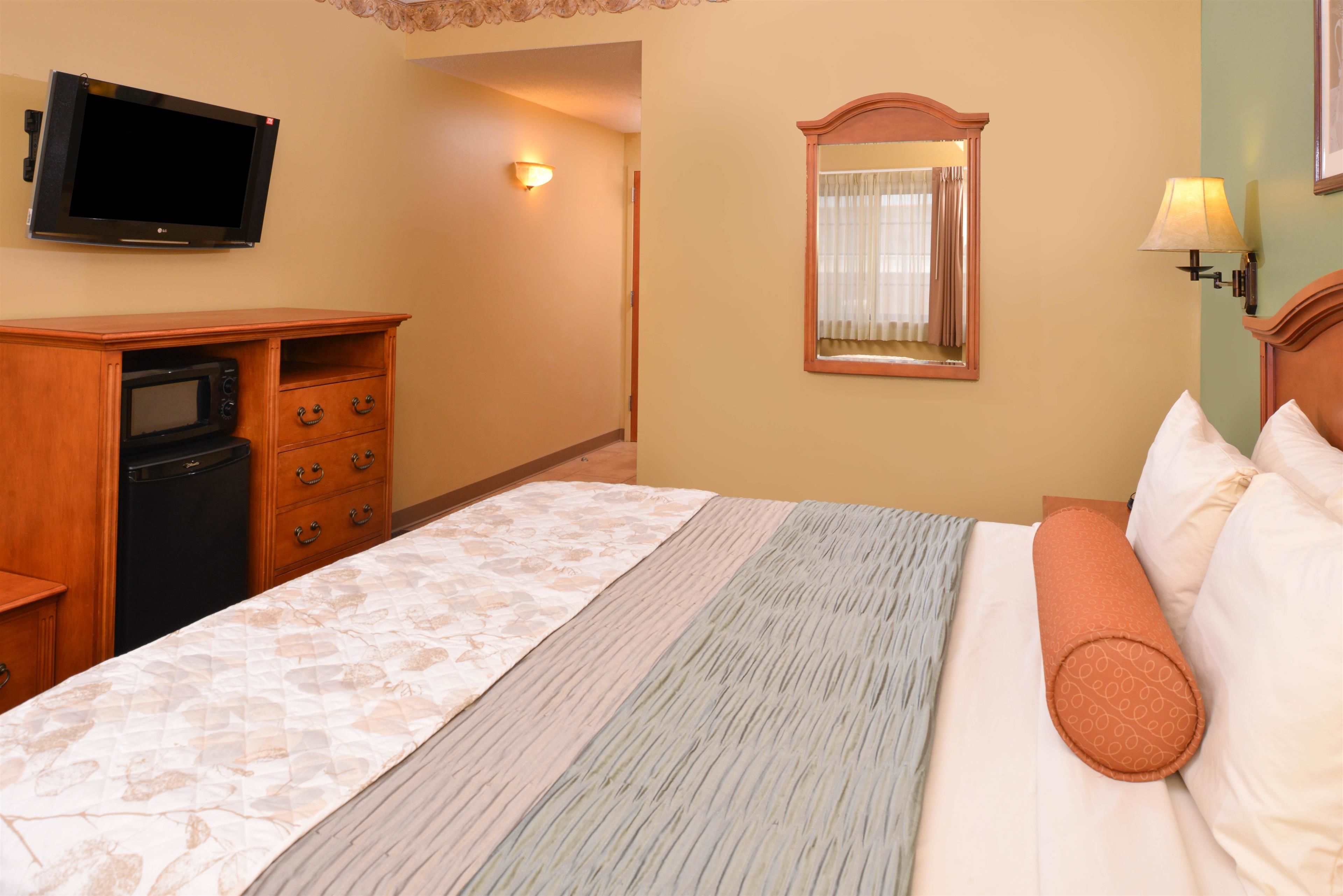 Une chambre d’hôtel équipée d’un lit, d’un téléviseur fixé au mur, d’un miroir et d’un petit bureau avec un micro-ondes.