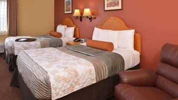 Quarto de hotel com duas camas, uma poltrona de couro marrom e duas luminárias fixadas na parede.