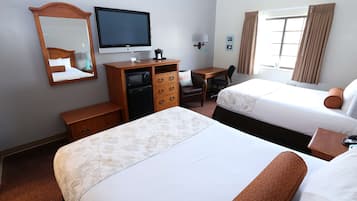 A hotel room with two beds, a desk, a television, a dresser, and a window with curtains.