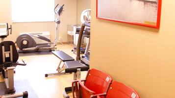 Un gimnasio con equipo de ejercicio, un televisor y una silla roja.