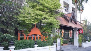 Entrada de un hotel con un gran letrero que dice 'Home', un porche cubierto y un cartel de 'No Entrar'.