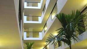 Interior de varios niveles con un atrio central, que cuenta con balcones y plantas en macetas.