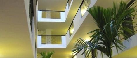 A multi-level interior with a central atrium, featuring balconies and potted plants.
